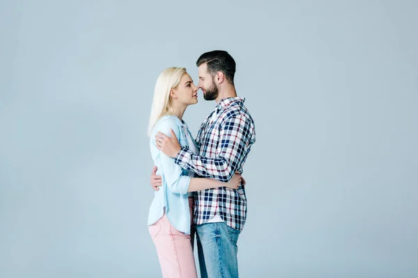 Schönes Paar, das sich umarmt und einander isoliert auf grau ansieht — Stockfoto