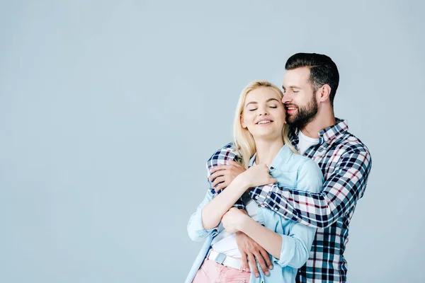 Schöner Mann umarmt schöne lächelnde junge Frau isoliert auf grau mit Kopierraum — Stockfoto