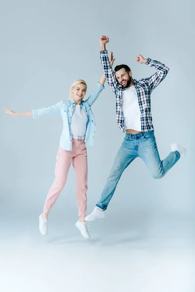 Glücklicher Mann und Mädchen in lässiger Kleidung springen auf grau — Stockfoto