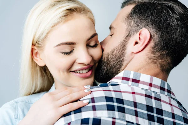 Mann küsst und umarmt lächelndes Mädchen isoliert auf grau — Stockfoto