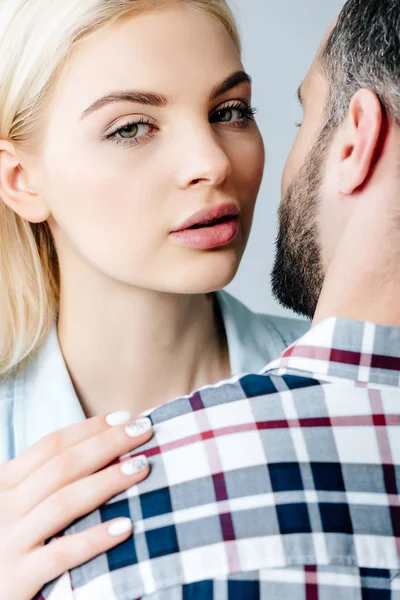 Schöne Mädchen umarmt Mann und schaut in Kamera isoliert auf grau — Stockfoto