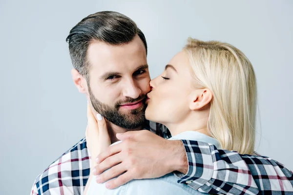 Hermosa rubia chica besos guapo hombre aislado en gris - foto de stock