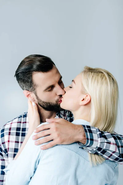 Beautiful young couple kissing and embracing isolated on grey — Stock Photo