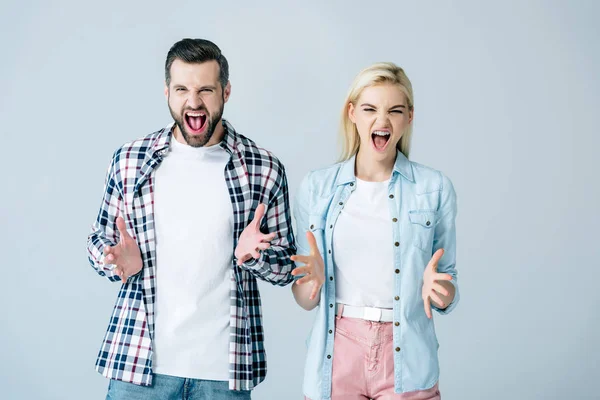 Man and woman looking at camera, shouting and gesturing isolated on grey — Stock Photo