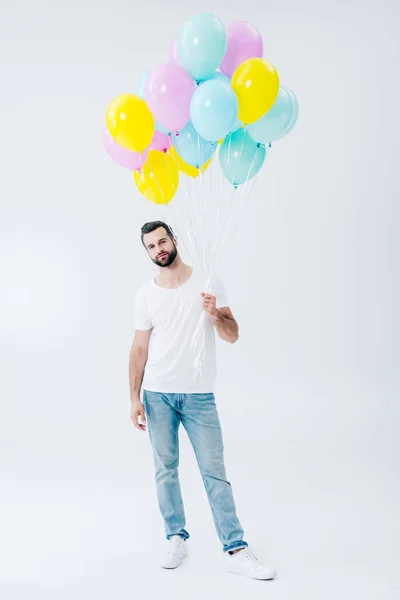 Uomo in abiti casual con palloncini colorati sul grigio e guardando la fotocamera — Foto stock