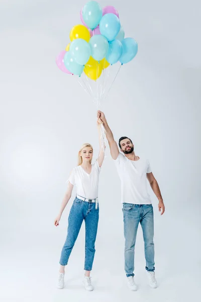 Hombre y hermosa chica sosteniendo globos en gris - foto de stock