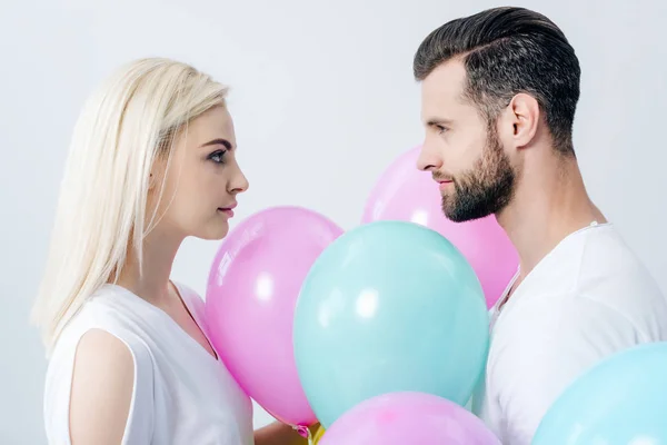 Man and beautiful girl with balloons looking at each other isolated on grey — Stock Photo