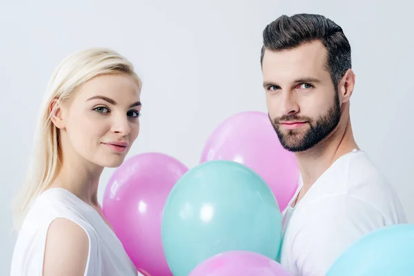 Mann und schönes Mädchen mit Luftballons schauen vereinzelt in die Kamera auf grau — Stockfoto