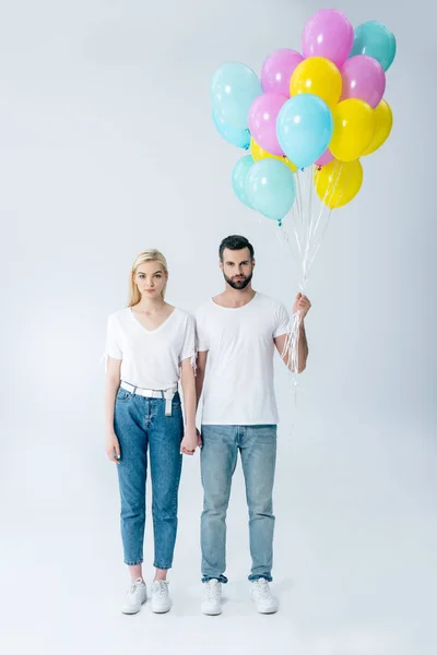 Man and beautiful girl with balloons looking at camera on grey — Stock Photo