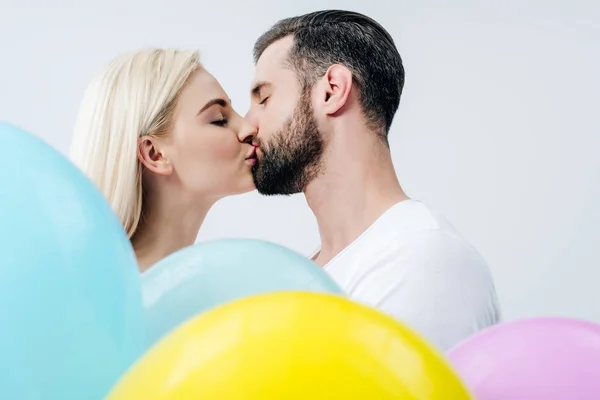 Uomo e bella ragazza con palloncini baciare isolato su grigio — Foto stock