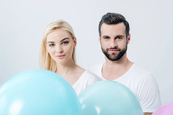 Man and beautiful girl with balloons looking at camera isolated on grey — Stock Photo