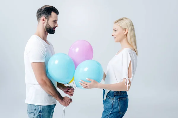 Man and beautiful girl holding balloons on grey — Stock Photo