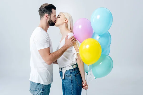 Bello uomo e bella ragazza con palloncini baci isolato su grigio — Foto stock