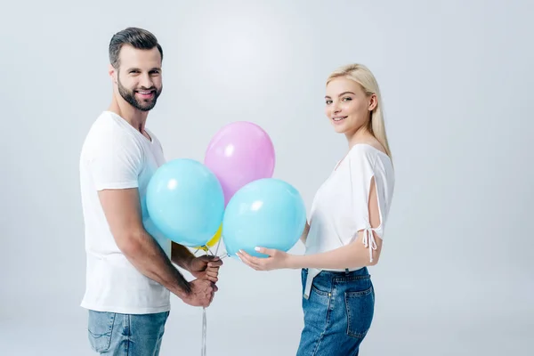 Lächelnder Mann und schönes Mädchen mit Luftballons auf grau — Stockfoto