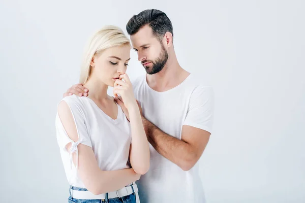 Handsome man embracing upset young woman isolated on grey — Stock Photo