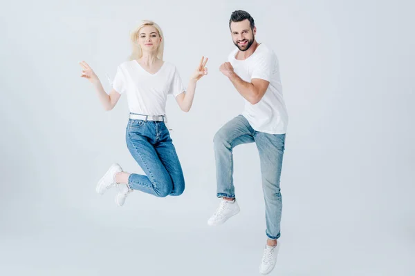 Excited man and young woman jumping isolated on grey — Stock Photo