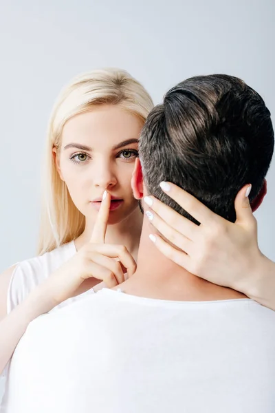 Beautiful girl embracing man and doing silence gesture isolated on grey — Stock Photo