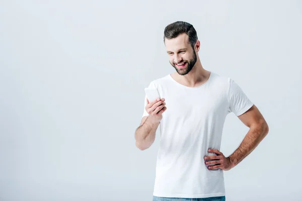 Uomo bello sorridente utilizzando smartphone isolato su grigio — Foto stock