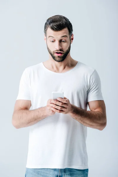 Homme choqué en utilisant smartphone isolé sur gris — Photo de stock