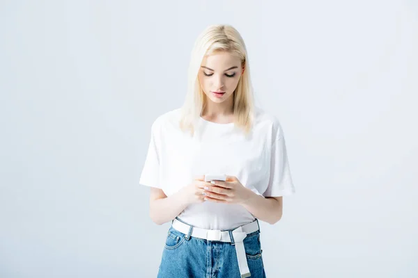 Красива блондинка використовує смартфон ізольовано на сірому — стокове фото
