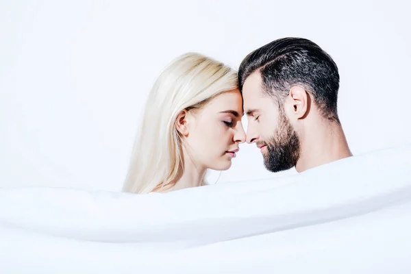 Girlfriend and boyfriend covered in blanket touching foreheads isolated on white — Stock Photo