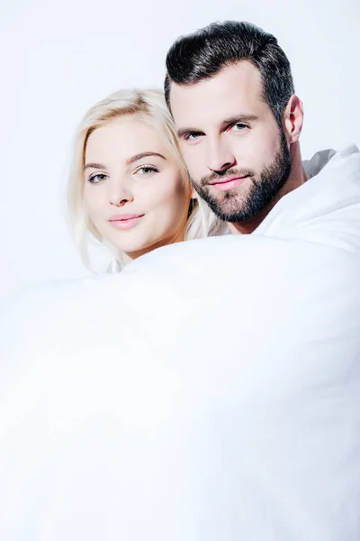 Girlfriend and boyfriend covered in blanket looking at camera isolated on white — Stock Photo