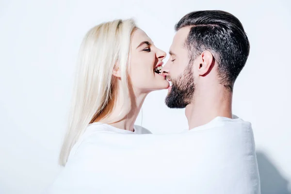 Girlfriend biting nose of boyfriend covered in blanket on white — Stock Photo