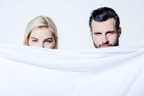 Girlfriend and boyfriend holding blanket and looking at camera isolated on white — Stock Photo