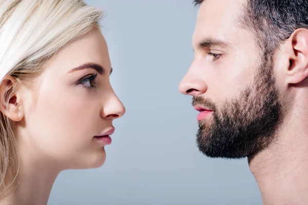 Handsome man and young woman looking at each other isolated on grey — Stock Photo