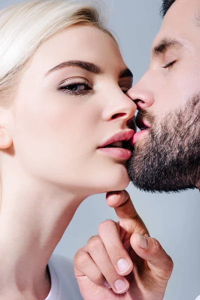 Schöner Mann küsst schöne blonde Mädchen isoliert auf grau — Stockfoto