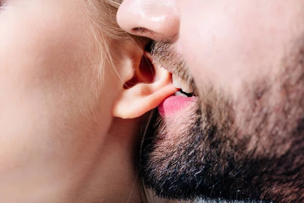 Nahaufnahme eines Mannes, der junge Frau ins Ohr beißt — Stockfoto