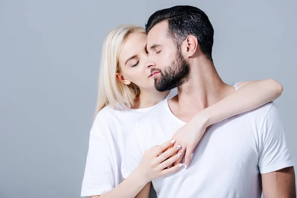 Menina bonita com os olhos fechados abraçando o homem isolado no cinza — Fotografia de Stock