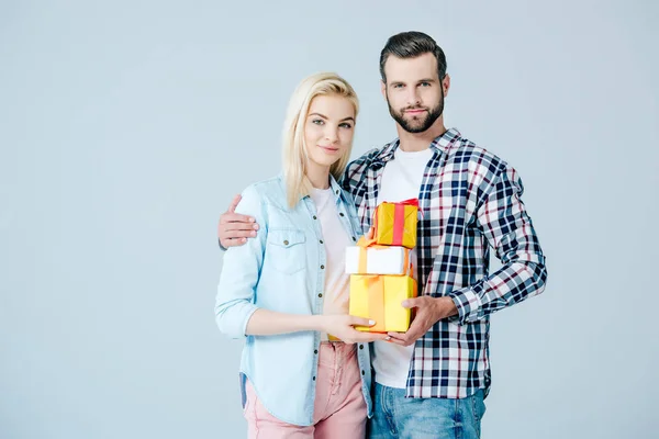 Hombre y hermosa chica sosteniendo regalos aislados en gris - foto de stock