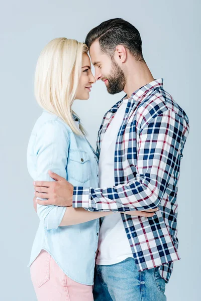 Beautiful young couple hugging and looking at each other isolated on grey — Stock Photo