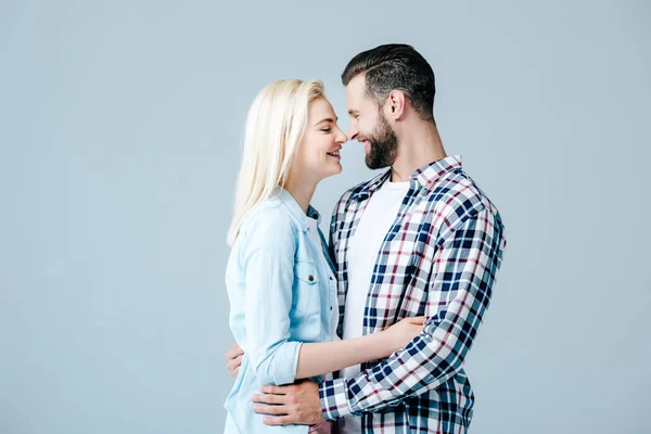 Hermosa pareja joven abrazándose y mirándose aislados en gris - foto de stock