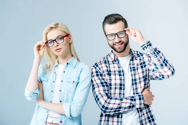 Hombre y chica ajustando gafas y mirando a la cámara en gris — Stock Photo