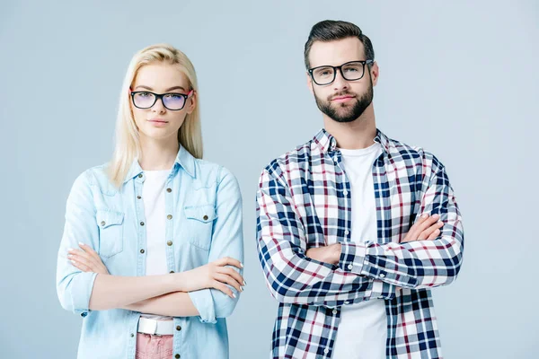 Uomo e bella ragazza in occhiali con le braccia incrociate isolato su grigio — Foto stock