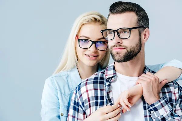Schönes Mädchen mit Brille umarmt Mann isoliert auf grau — Stockfoto