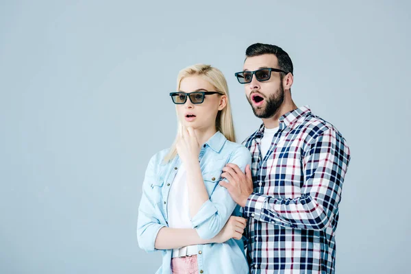 Sorprendido hombre y chica en 3d gafas viendo película aislado en gris - foto de stock