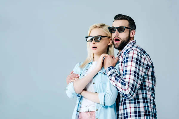 Переляканий чоловік і дівчина в 3d окулярах тримають руки під час перегляду фільму ізольовані на сірому — стокове фото