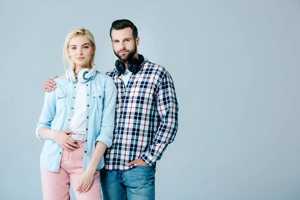 Uomo e ragazza con le cuffie guardando la fotocamera isolata su grigio con spazio copia — Foto stock