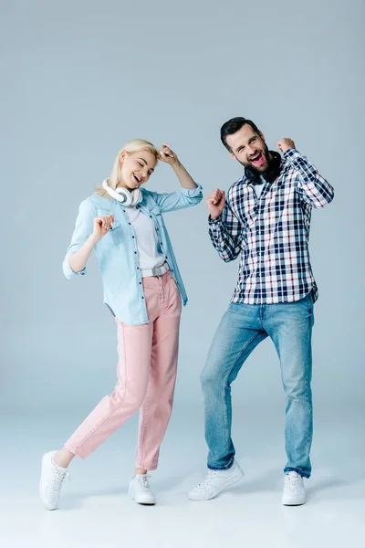 Feliz hombre y chica con auriculares bailando en gris - foto de stock
