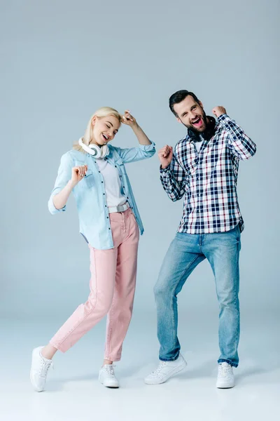 Happy man and girl with headphones dancing on grey — Stock Photo