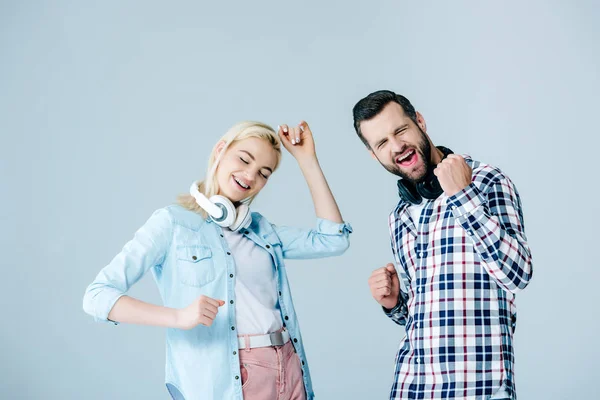 Happy man and girl with headphones dancing isolated on grey — Stock Photo