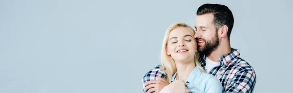 Panoramaaufnahme eines gutaussehenden Mannes, der die schöne lächelnde junge Frau umarmt, isoliert auf grau — Stockfoto