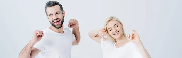 Panoramic shot of happy man and young woman stretching with clenched fists isolated on grey — Stock Photo