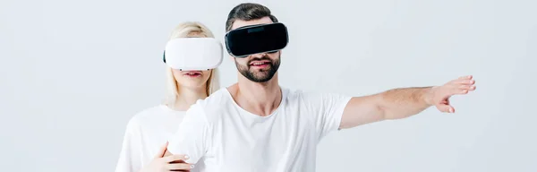 Panoramic shot of gesturing man and girl in Virtual reality headsets isolated on grey — Stock Photo