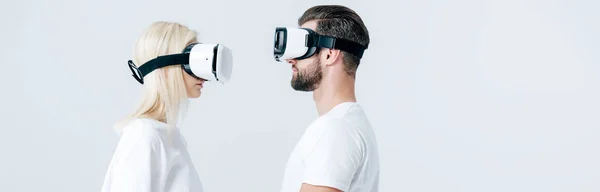 Панорамний знімок чоловіка і дівчини в гарнітурах віртуальної реальності ізольовані на сірому — стокове фото