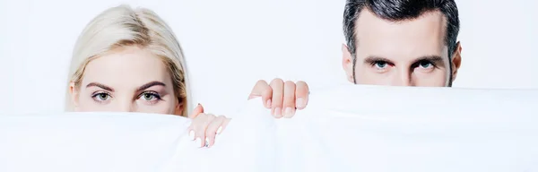 Panoramic shot of beautiful girlfriend and handsome boyfriend holding blanket isolated on white — Stock Photo