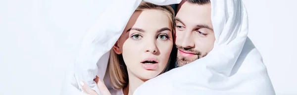 Panoramic shot of attractive girlfriend and boyfriend covered in blanket isolated on white — Stock Photo